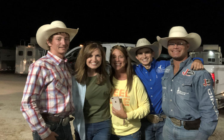 A group of men and women hugging in front of trucks and trailers.